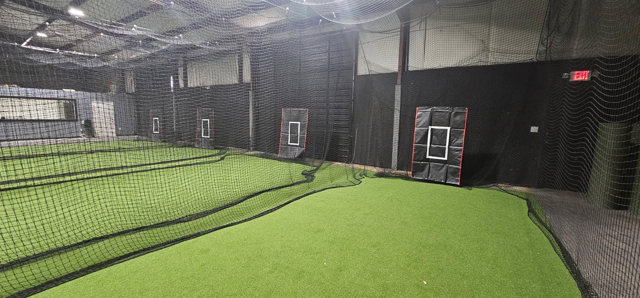 Indoor baseball training space with turf and netted lanes